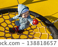 Little girl in sunglasses sits on a rope swing at the playground 138818657