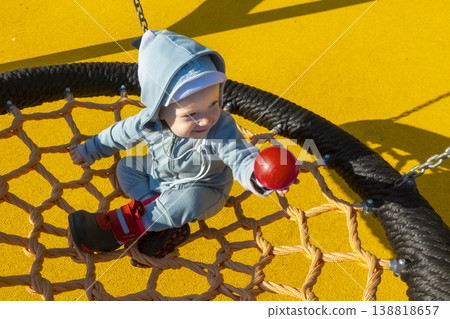 Little girl in sunglasses sits on a rope swing at the playground Little girl in sunglasses sits on a rope swing at the playground 138818657