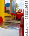 Child with red raincoat of firefighter clings to a rope in a playground during rain. 138818658