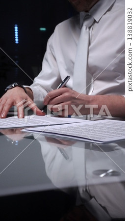 Business man signing a contract late in the office, closing a deal, or completing legal paperwork at deep night. Audit and overworking concepts 138819032