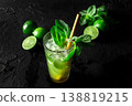 Mojito, summer cocktail with mint and ice, a single glass on black with limes 138819215