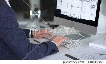 Architect working on building design project using computer cad software and blueprints at office desk. Business and architecture concept Architect working on building design project using computer cad software and blueprints at office desk. Business and architecture concept 138819360
