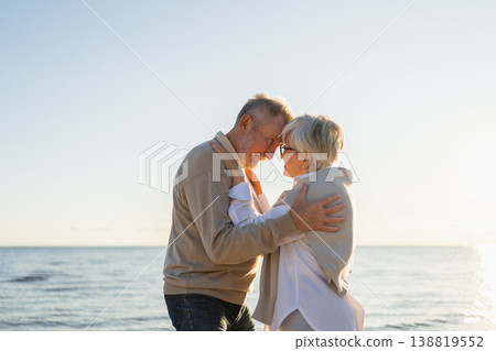 Senior mature couple hugging enjoying outdoor recreation walking on beach. Old husband wife embracing with tenderness love enjoying sweet bonding. Grandmother grandfather together. Family moment love 138819552