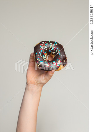 Chocolate Donut in human hand. Tasty doughnut, sweet dessert food Chocolate Donut in human hand. Tasty doughnut, sweet dessert food 138819614