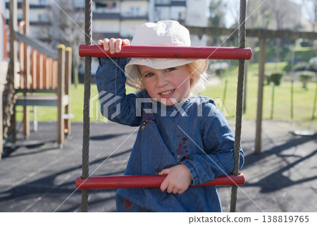 4 year old girl playing on a playground and climbing a rope ladder 138819765