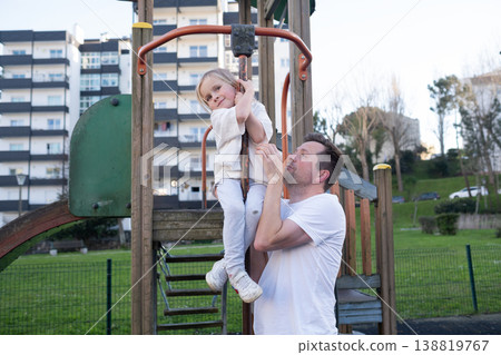 Middle-aged father carrying his 4 year old daughter while walking outdoors 138819767