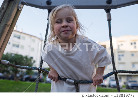 Active 4 year old girl climbing up a rope ladder at the playground Active 4 year old girl climbing up a rope ladder at the playground 138819772