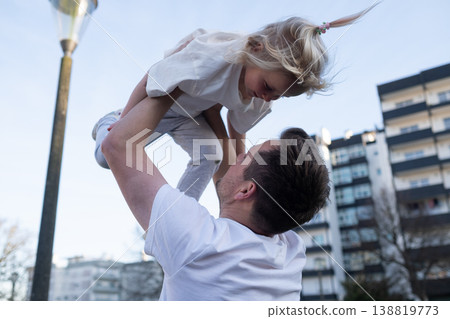 Playful 4 year old girl being thrown in the air by her father outdoors Playful 4 year old girl being thrown in the air by her father outdoors 138819773