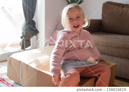 Curious 4 year old girl sitting on a huge delivery box and wondering what is inside Curious 4 year old girl sitting on a huge delivery box and wondering what is inside 138819819