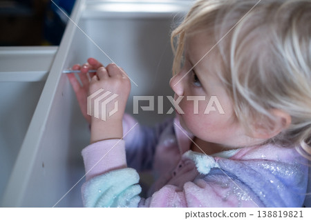 Independent 4 year old girl assembling furniture with a screwdriver in a modern home interior Independent 4 year old girl assembling furniture with a screwdriver in a modern home interior 138819821