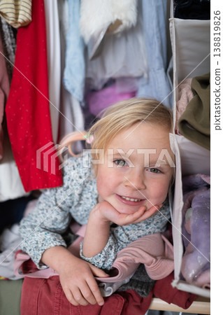 Little 4 Year Old Caucasian Girl Playing Hide-and-Seek Inside a Cluttered Clothes Wardrobe 138819826