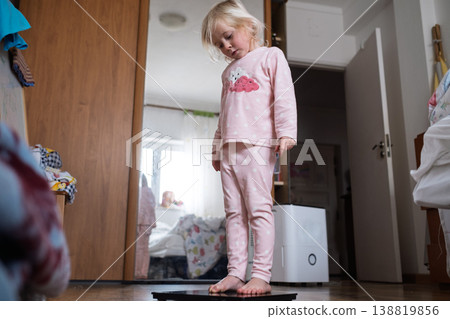 Cute 4 year old Caucasian girl standing on weighing scales Cute 4 year old Caucasian girl standing on weighing scales 138819856