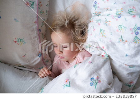 Peaceful 4 year old girl sleeping in cozy pajamas in a sunlit bedroom 138819857