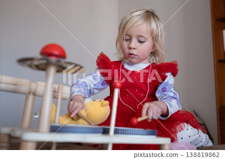 Creative 4 year old girl teaching her teddy bear to play the drums in a stylish modern playroom Creative 4 year old girl teaching her teddy bear to play the drums in a stylish modern playroom 138819862