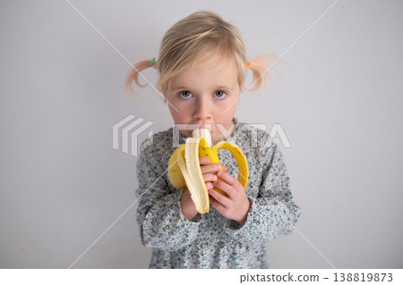 Healthy Snack Time: Charming 4 year old girl enjoying a fresh banana in a bright modern kitchen Healthy Snack Time: Charming 4 year old girl enjoying a fresh banana in a bright modern kitchen 138819873