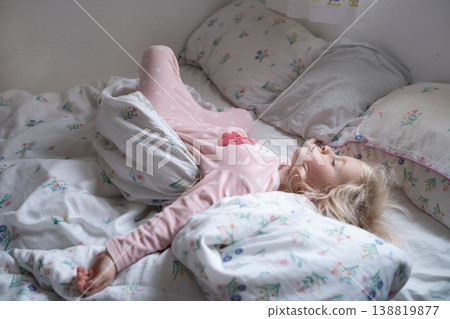 Peaceful 4 year old girl sleeping in cozy pajamas in a sunlit bedroom Peaceful 4 year old girl sleeping in cozy pajamas in a sunlit bedroom 138819877