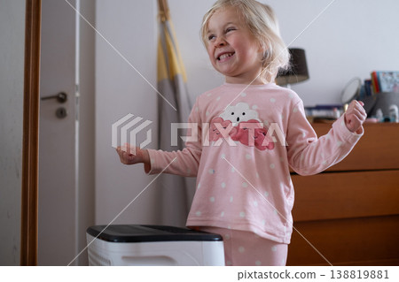 Independent 4 year old girl turning on a modern air dehumidifier to control humidity in her room Independent 4 year old girl turning on a modern air dehumidifier to control humidity in her room 138819881