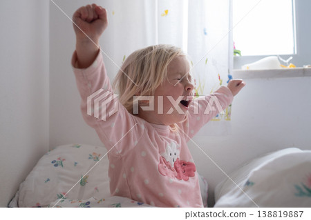 Adorable 4 year old girl yawning and stretching after waking up in a cozy sunlit bedroom Adorable 4 year old girl yawning and stretching after waking up in a cozy sunlit bedroom 138819887