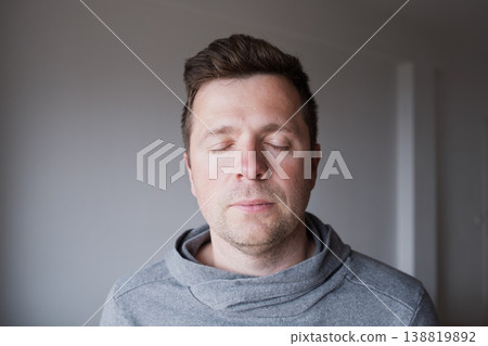 Serene middle aged Caucasian man standing with closed eyes, enjoying a peaceful moment  138819892