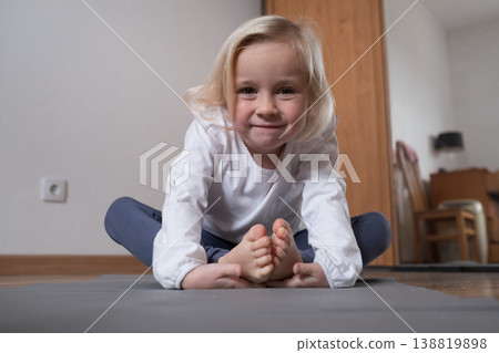 Little girl practicing yoga in Butterfly pose Baddha Konasana at home. Little girl practicing yoga in Butterfly pose Baddha Konasana at home. 138819898