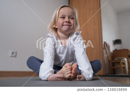 Little girl practicing yoga in Butterfly pose Baddha Konasana at home. Little girl practicing yoga in Butterfly pose Baddha Konasana at home. 138819899