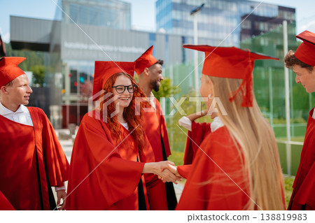 Graduates congratulating each other with handshake during university graduation ceremony. 138819983