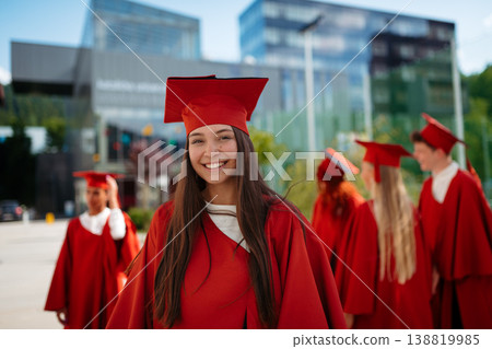 Smiling young female graduate in cap and gown during university graduation ceremony. 138819985