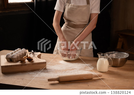 Baker kneading dough in glass bowl for homemade bread on floury wooden kitchen counter in rustic setting Baker kneading dough in glass bowl for homemade bread on floury wooden kitchen counter in rustic setting 138820124