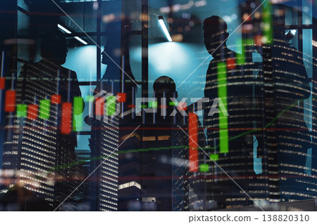 Business people discuss financial charts at night inside an office building with city lights in the background Business people discuss financial charts at night inside an office building with city lights in the background 138820310