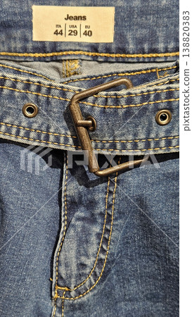 Fragment of blue jeans with a fly, a belt, and a size label 138820383