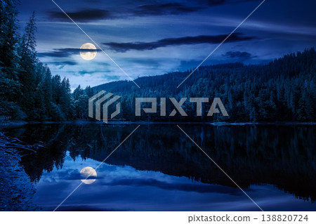 landscape by the lake at night. full moon over coniferous forest near the lake and the forest mountain. mysterious summer view of carpathian mountain reflection on synevr lake water surface 138820724