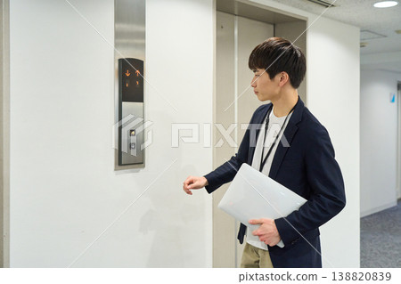 A young businessman waiting for the elevator with his laptop. A young businessman waiting for the elevator with his laptop. 138820839