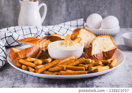 Egg sauce in a bowl, breadsticks and bread on a plate on the table 138821037