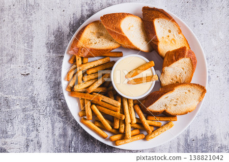 Close up of egg sauce in a bowl, breadsticks and bread on a plate on the table top view 138821042