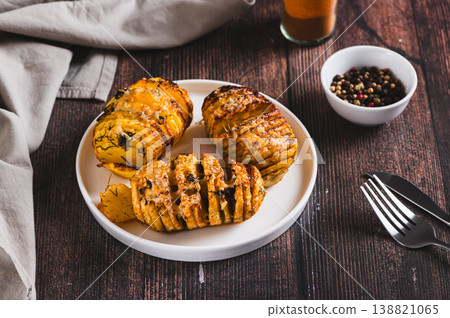 Crispy baked accordion potatoes with cheese and herbs on a plate on the table Crispy baked accordion potatoes with cheese and herbs on a plate on the table 138821065