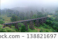 Foggy mountain railway bridge shrouded in mist and lush greenery. 138821697