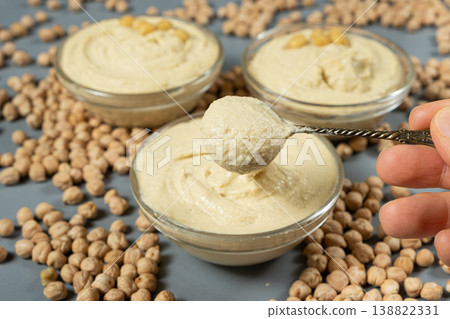 Traditional hummus in a spoon among scattered raw chickpeas. 138822331