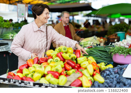 Mature casual female choosing fresh local organic vegetables for upcoming cooking at bazaar Mature casual female choosing fresh local organic vegetables for upcoming cooking at bazaar 138822400