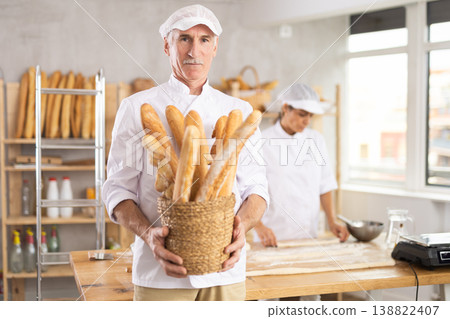 Elderly man with basket of baguettes in bakery Elderly man with basket of baguettes in bakery 138822407