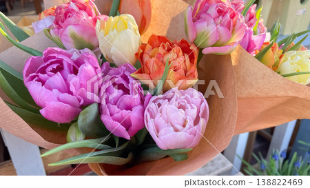 Beautiful bouquets of colorful double peony tulips wrapped in craft paper in soft morning sunlight 138822469