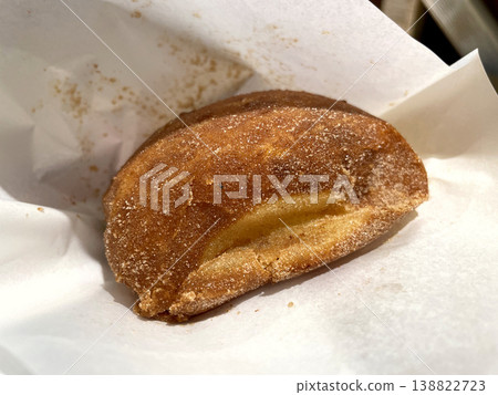 Malasada cross-section - A fried donut with custard cream peeking out. Malasada cross-section - A fried donut with custard cream peeking out. 138822723