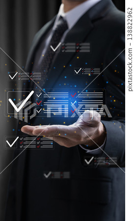 A professional businessman interacts with a futuristic digital interface showing completed checklists, symbolizing task management, quality control, and efficient business workflow 138822962