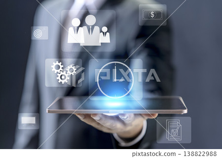 Businessman holding a tablet featuring digital icons for time, human resources, finance, and goals, representing modern enterprise management and digital transformation technology 138822988