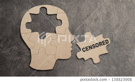 Conceptual image of a jigsaw puzzle in the shape of a human profile with a central piece removed and labeled CENSORED, representing memory loss, suppression, and mental health issues 138823008