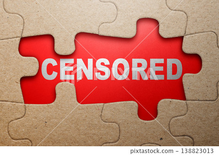 A jigsaw puzzle with missing pieces reveals a bright red background with the word CENSORED in silver, representing media restriction and hidden information concepts A jigsaw puzzle with missing pieces reveals a bright red background with the word CENSORED in silver, representing media restriction and hidden information concepts 138823013