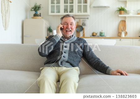 Happy middle aged senior man talking on smartphone with family friends. Older mature grandfather with cell phone talking with grown up children, resting at home. Older generation modern tech usage Happy middle aged senior man talking on smartphone with family friends. Older mature grandfather with cell phone talking with grown up children, resting at home. Older generation modern tech usage 138823603