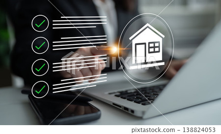 Business professional analyzing property listings on a laptop, checking tasks with a graphical home icon in a modern workspace environment Gantry Business professional analyzing property listings on a laptop, checking tasks with a graphical home icon in a modern workspace environment Gantry 138824053