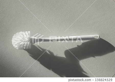 A white toilet brush is lying on the floor. 138824329
