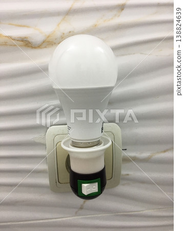 Light bulb is plugged into a wall socket showing hardware and design features in modern interior Light bulb is plugged into a wall socket showing hardware and design features in modern interior 138824639