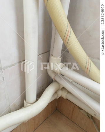 Pipes connect at a corner in a home setting during daylight hours 138824649